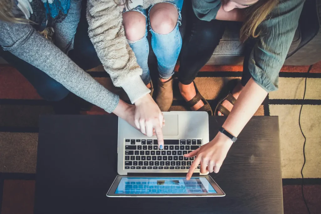 Three friends looking at the same laptop